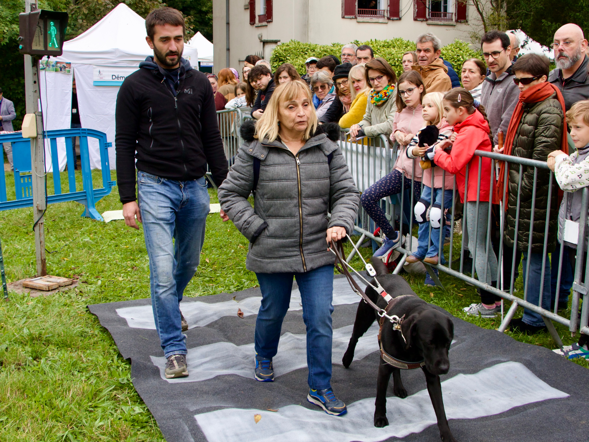 une maîtresse de chien guide réalise un parcours d'obstacle sous sous le regard d'un éducateur
