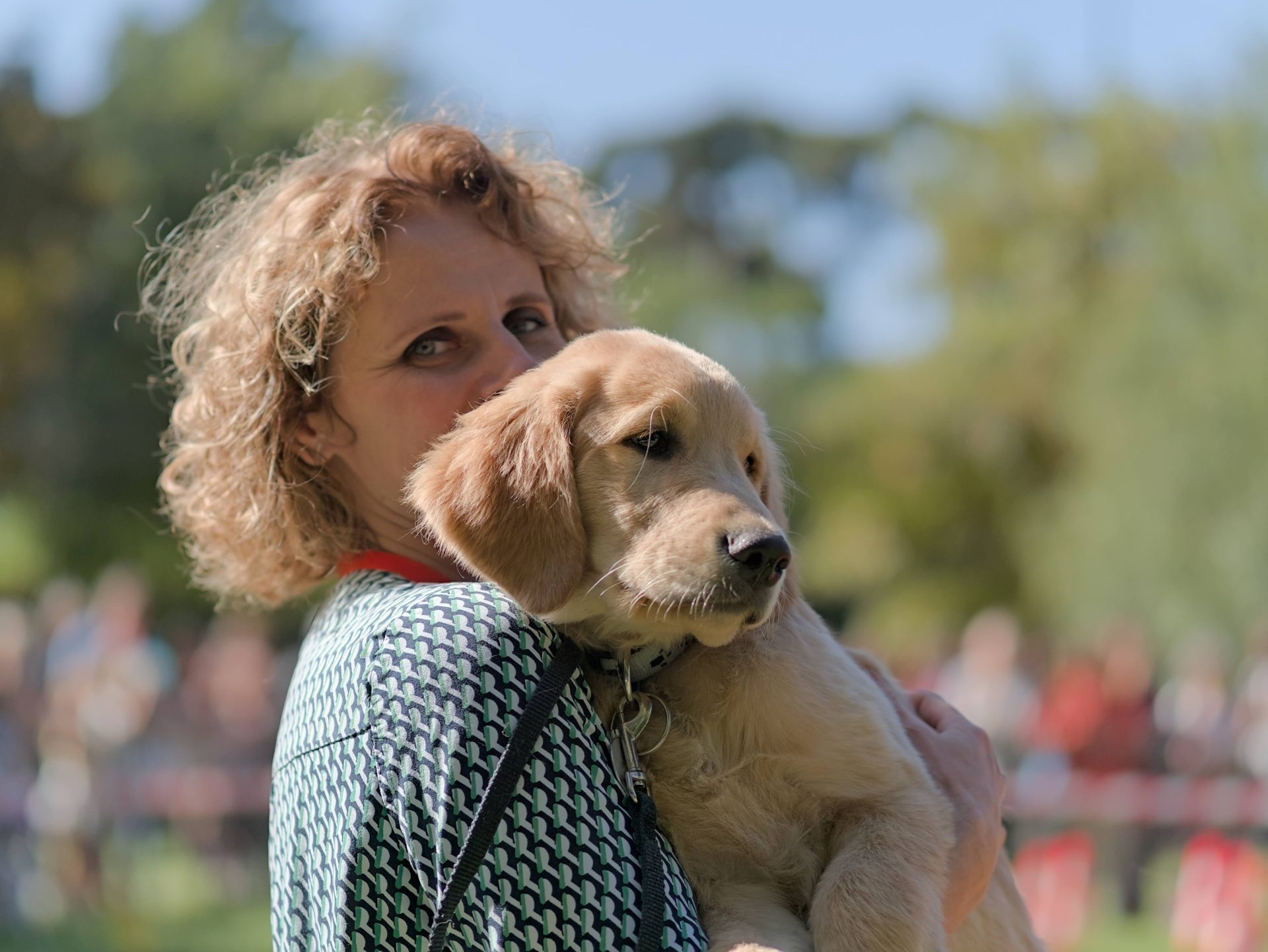La présidente de l'association sourit en tenant un chiot dans les bras
